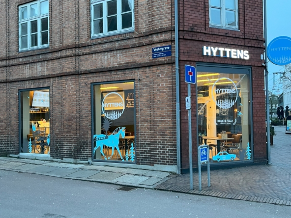 Udvendigt view af Hyttens Pizzeria i Randers, der viser restaurantens facade og indgang.