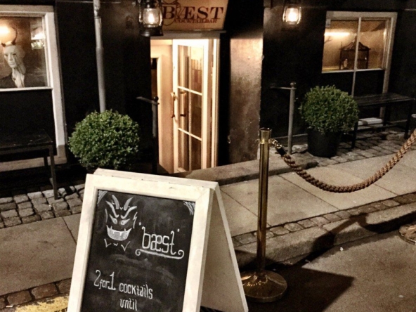 Facade af Bæst Cocktailbar København om natten med oplyst navneskilt